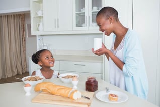 Portrait smiling mother and daughter eating together at home in the kitchen_11zon